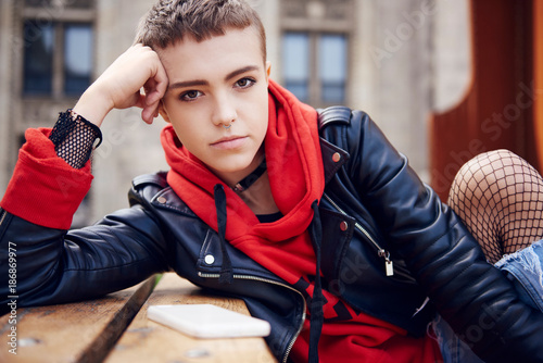 Portrait of cool young woman with short hair at city bench