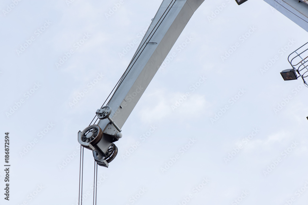 Shot of an old, rusty port crane preparing to lift cargo in ship on overcast sky background. Equipment for unloading ships and barges, preparing for export world wide Shot of an old, rusty port crane preparing to lift cargo in ship on overcast sky background. Equipment for unloading ships and barges, preparing for export world wide