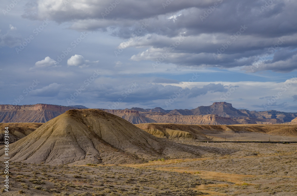 Fototapeta premium white clouds over Christmas Ridge and deserted hills near Crescent Junction, Grand County, Utah