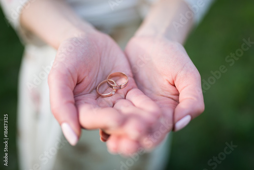 Golden wedding ring and engagement ring in hands of woman.