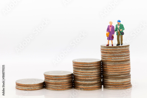Miniature people, Old couple figure standing on top of stack coins using as background retirement planning, Life insurance concept.
