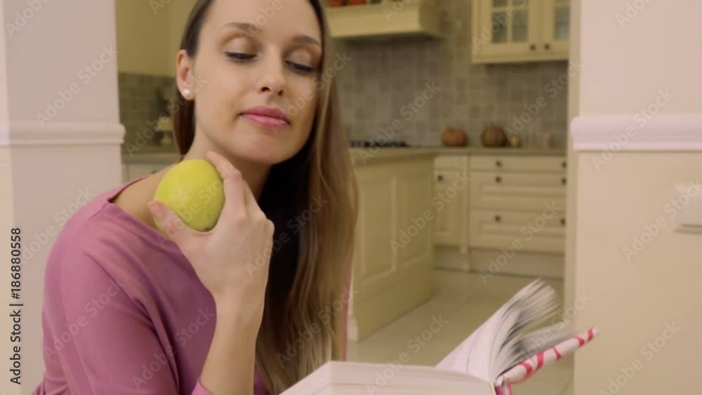 Young woman eats apple and read the book