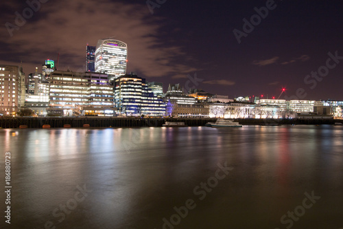 London Skyline at Night featuring the Walkie Talkie building and City Hall.  Long exposure gives the Thames River a smooth and glassy look. 