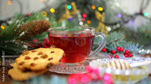 a cup of tea with honey and cookies, a branch of a Christmas tree in the snow, Christmas lights