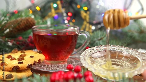 a cup of tea with honey and cookies, a branch of a Christmas tree in the snow, Christmas lights