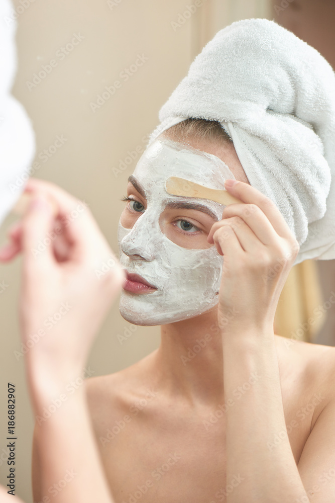 Facials. A girl with a towel on his head and a mask on her face