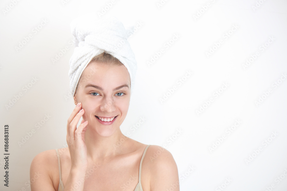 Skin care. Young woman on white background with towel on head touching her clean skin on the face Skin care. Young woman on white background with towel on head touching her clean skin on the face