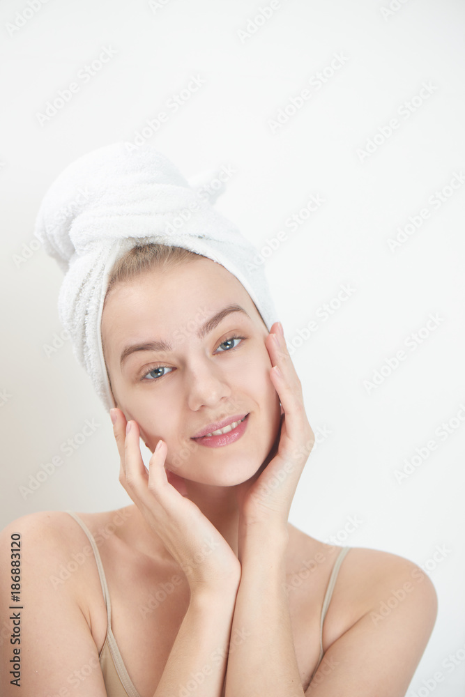 Skin care. Young woman on white background with towel on head touching her clean skin on the face Skin care. Young woman on white background with towel on head touching her clean skin on the face
