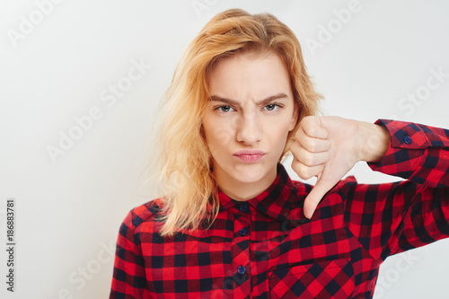 Unhappy young girl holding a thumbs down © amixstudio