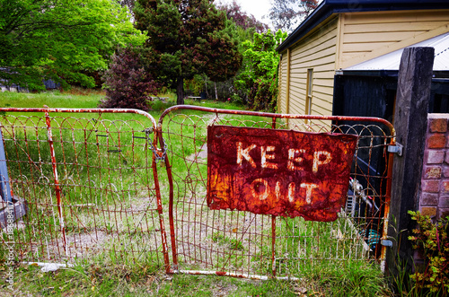 Old rustic keep out sign on metal gate