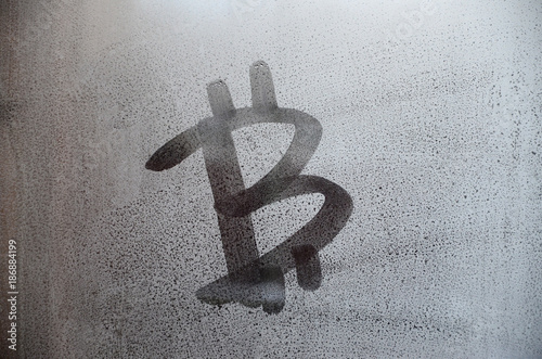 The bitcoin symbol on the misted sweaty glass. Abstract background image. Cryptocurrency concept photo