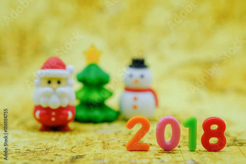 2018 New year Concept. Closeup of colorful plastic number with on world map with minature Santa Claus christmas tree and snowman figure.