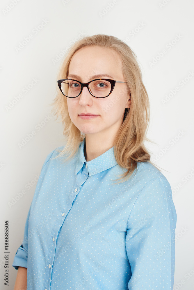 Portrait of business girl on a white background in a blue shirt and glasses Portrait of business girl on a white background in a blue shirt and glasses