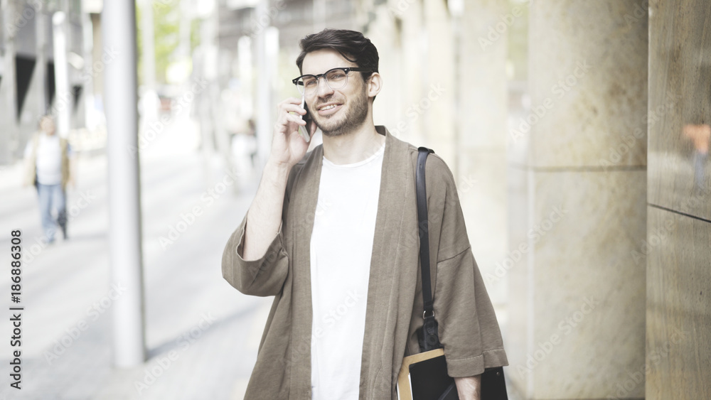 Medium shot portrait of a businessman walking towards camera and using a smart phone in the street. Medium shot portrait of a businessman walking towards camera and using a smart phone in the street.