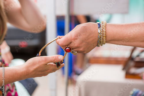 Woman with luxury gemstone rings and bracelets selling expensive jewelry. Shot of reaching hand for a necklace