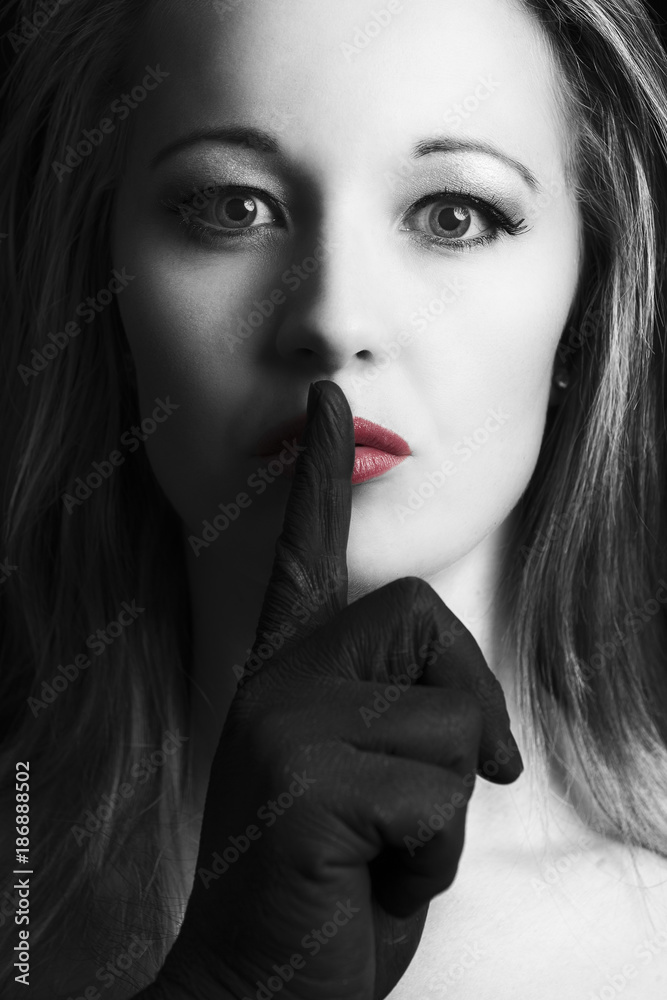 Frightened blonde woman silenced with finger in black on her face with red lips artistic conversion Frightened blonde woman silenced with finger in black on her face with red lips artistic conversion