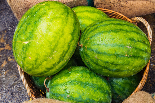 Fresh Watermelon in a basket, green and yellow watermelons in the market background