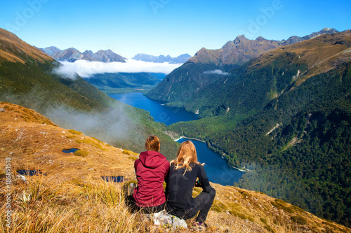 Travel couple in front of stunning mountain valley view in wild nature. Side trip from Key Summit's Route Burn Track with view of Lake Fergus