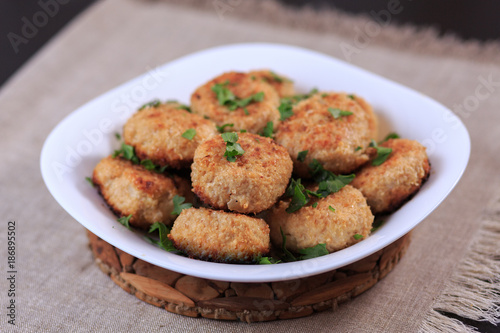 Fried cutlets on a white plate on a table on a gray background.