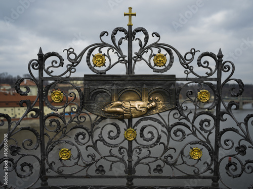 Iron forged grid with St. John of Nepomuk carving on the Charles Bridge, Prague, Czech Republic