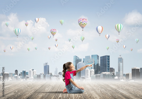 Tableau sur toile Concept of careless happy childhood with girl pointing at something