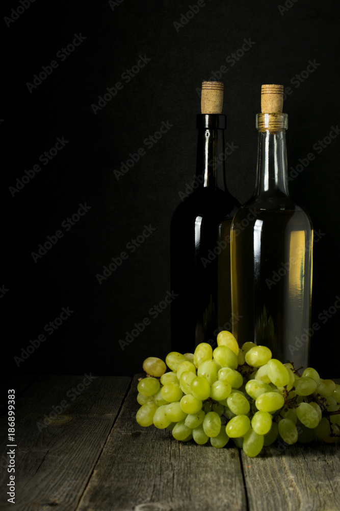 Obraz premium Glass bottle of wine with corks on wooden table background