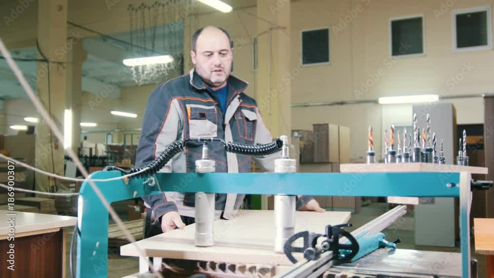 Carpenter handles a wooden fragment on a furniture factory Carpenter handles a wooden fragment on a furniture factory