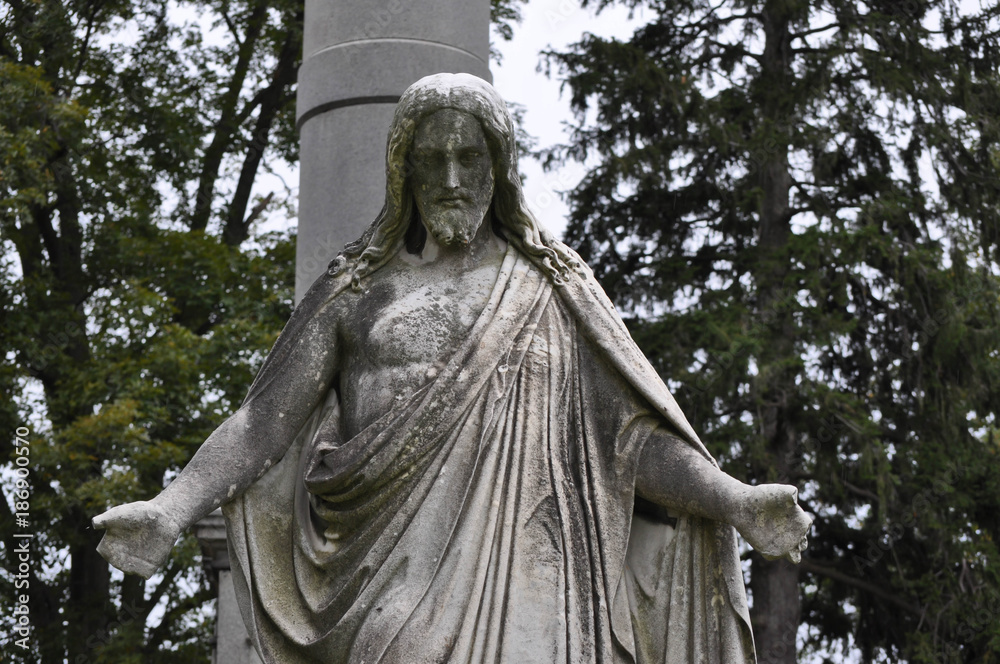 Statue of Jesus Looking Down Upon a Grave