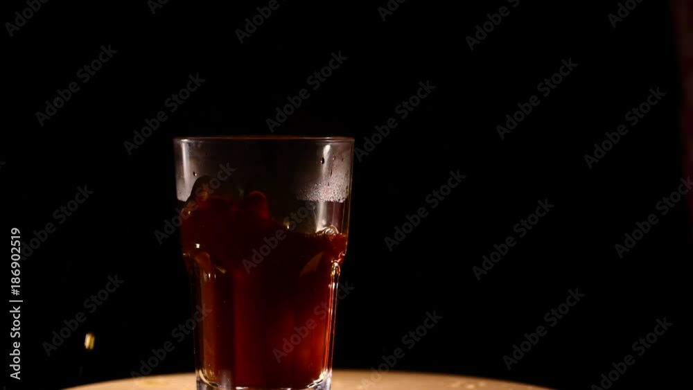 Ice dropping into glass of cocktail slowmo
