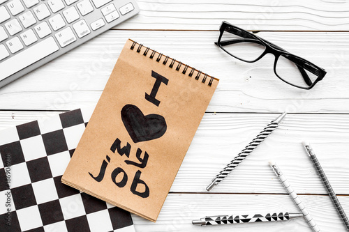 I love my job written in notebook at office desk on white wooden background top view photo