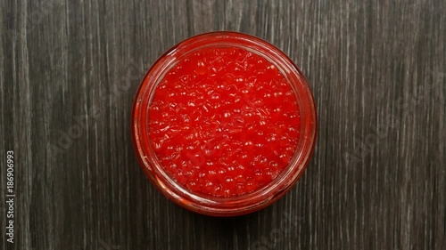 Opening jars with red caviar. Women's hands open a lid from a jar of red caviar. Top view
