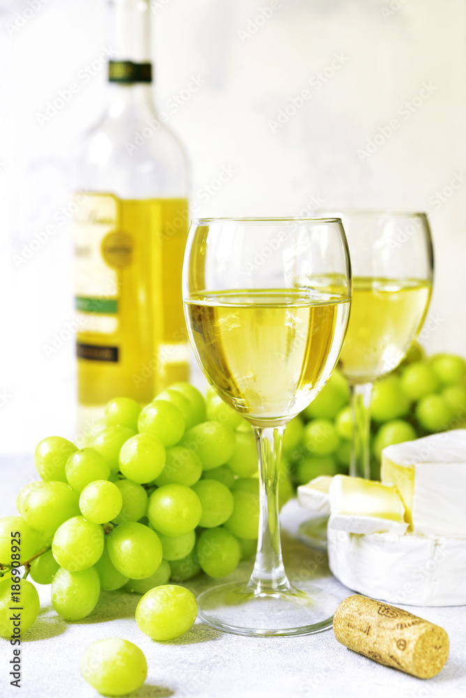 Two glasses of white wine,cheese and grapes . Two glasses of white wine,cheese and grapes .