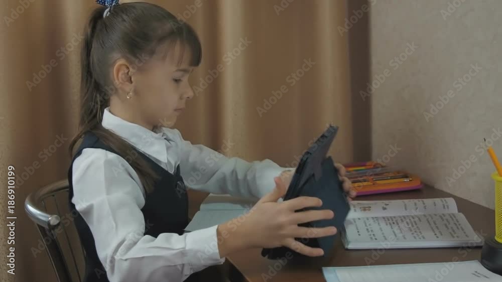 A child with a tablet and a book. A schoolgirl learns with a paper book and an e-book. A child with a tablet and a book. A schoolgirl learns with a paper book and an e-book.