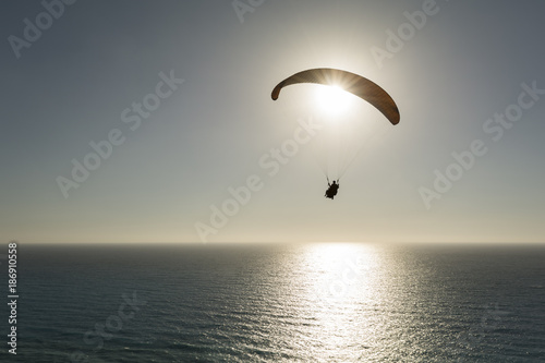 Silhouette of paraglider flying against sky