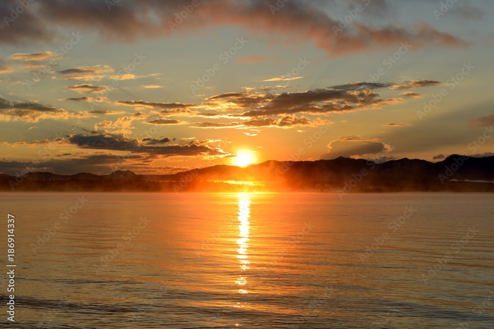 Naklejka premium Sunrise at Yellowstone Lake - A late August morning, the sun rises over the foggy Yellowstone Lake, Yellowstone National Park, Wyoming, USA.