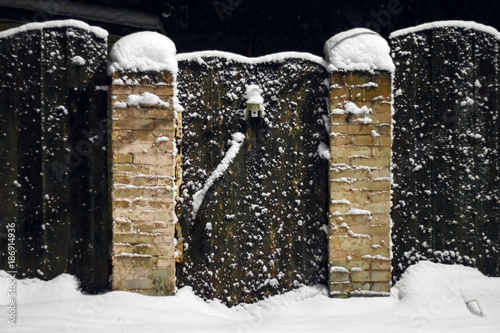 Door and fence are covered with snow in country house in winter
