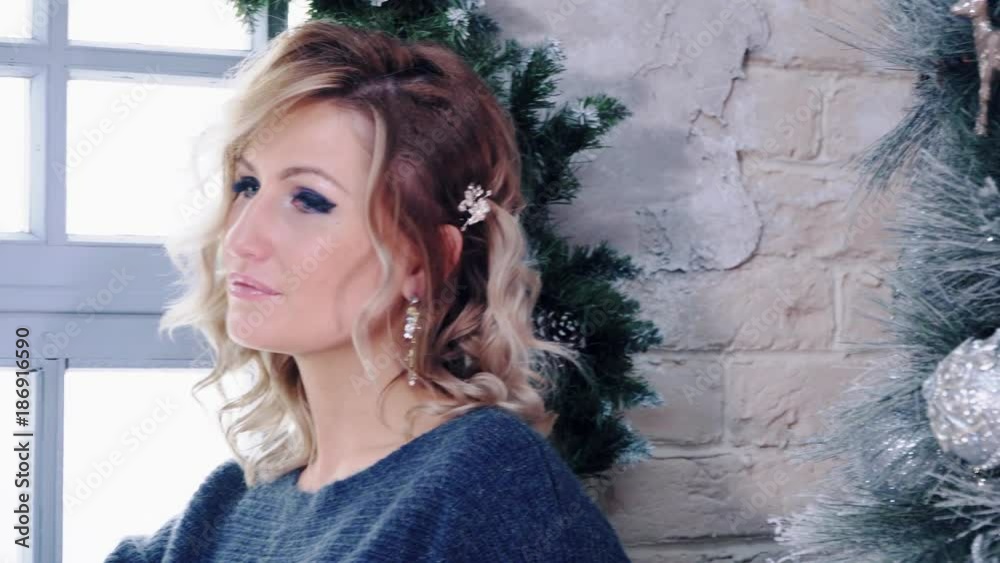 Cute blonde model posing near window and christmas tree. Cute blonde model posing near window and christmas tree.