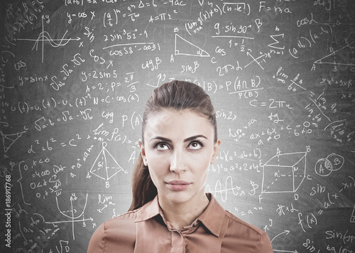Pensive woman in brown, formulas on blackboard