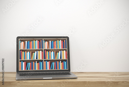 Laptop with bookshelves on screen, wooden desk
