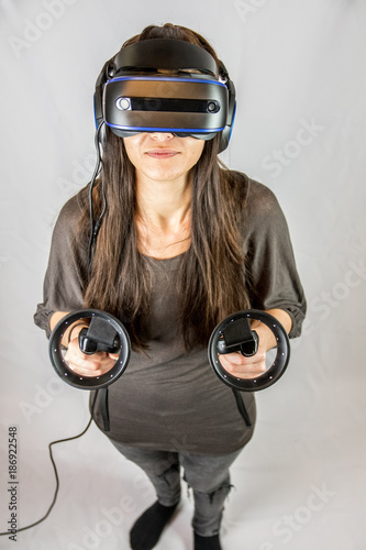 Junge Frau spielt mit Virtual Reality Datenbrille und Controllern (Vogelperspektive 3) photo