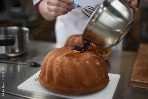 Pouring chocolate topping over cake