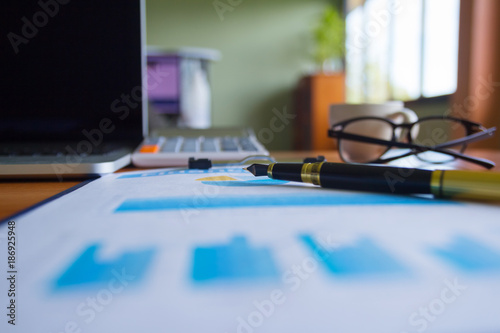 Pen keyboard calculator report graph chart on office table for Business.