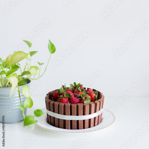 A chocolate cake with kitkat and strawberry on white desk. A very delicious cake.