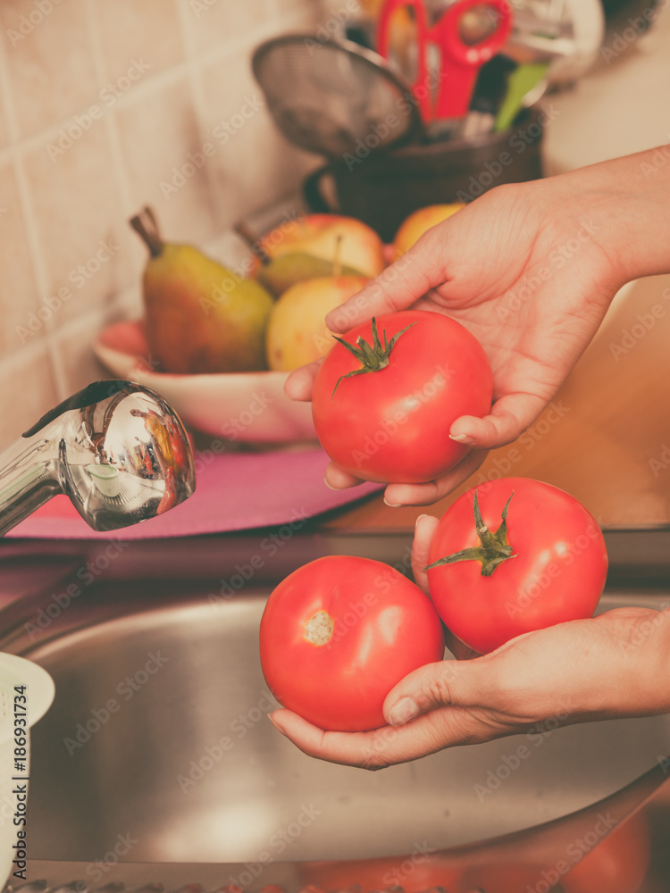 woman washing fresh vegetables in kitchen woman washing fresh vegetables in kitchen