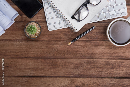 Office table with notebook, computer keyboard, mouse, cup of coffee, tablet pc and smartphone