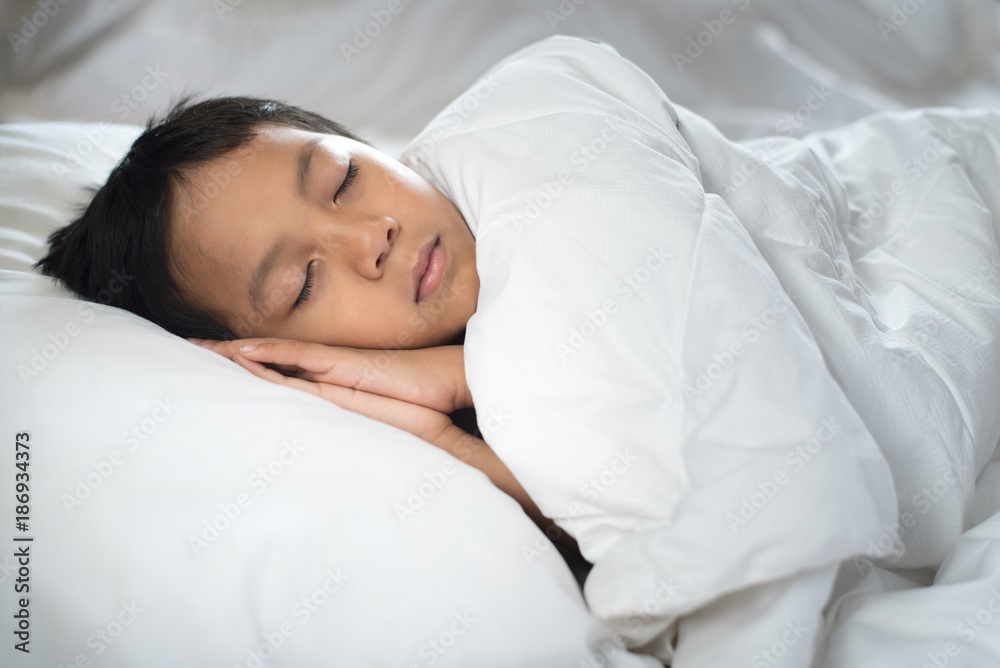 boy sleeping on bed with white sheet and pillow.asian kid fall asleep daydreaming.sleep concept boy sleeping on bed with white sheet and pillow.asian kid fall asleep daydreaming.sleep concept