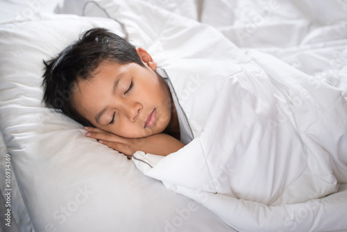 boy sleeping on bed with white sheet and pillow.asian kid fall asleep daydreaming.sleep concept