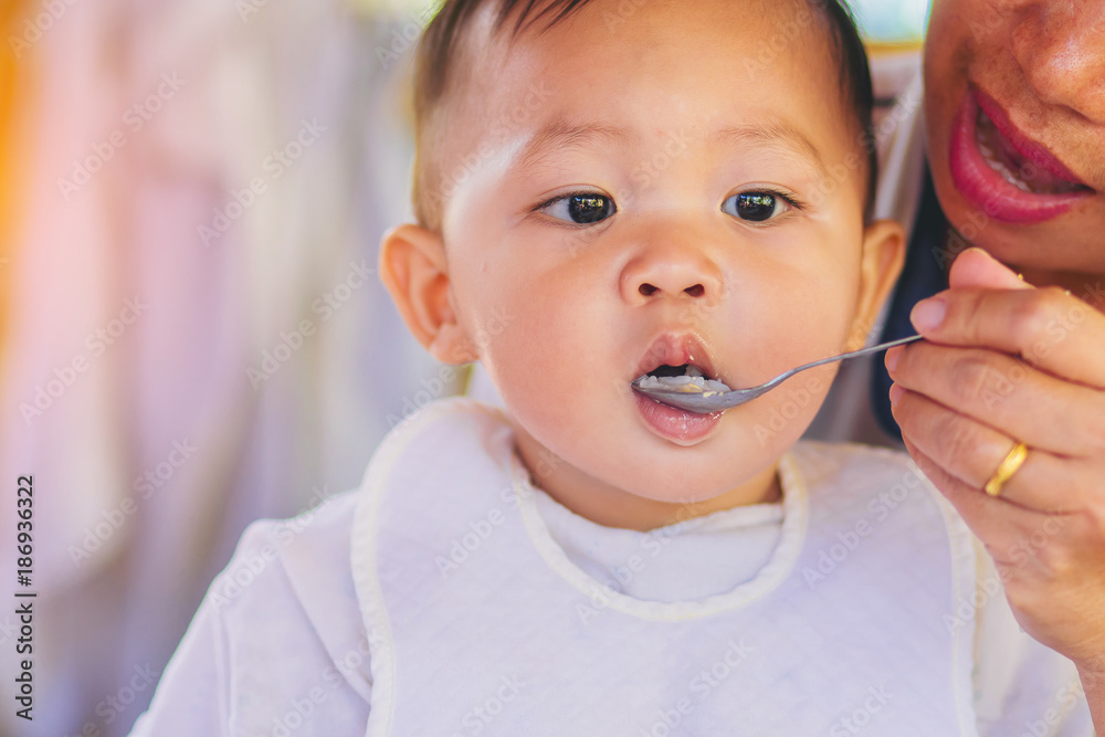 close up of mother feeding soft rice soup for little baby. close up of mother feeding soft rice soup for little baby.