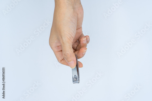 Adult female hand holding metallic nail clipper on white background