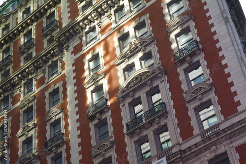 The side view of an orange and white bricked Manhattan, New York apartment building with rustic ornate and Victorian design photo